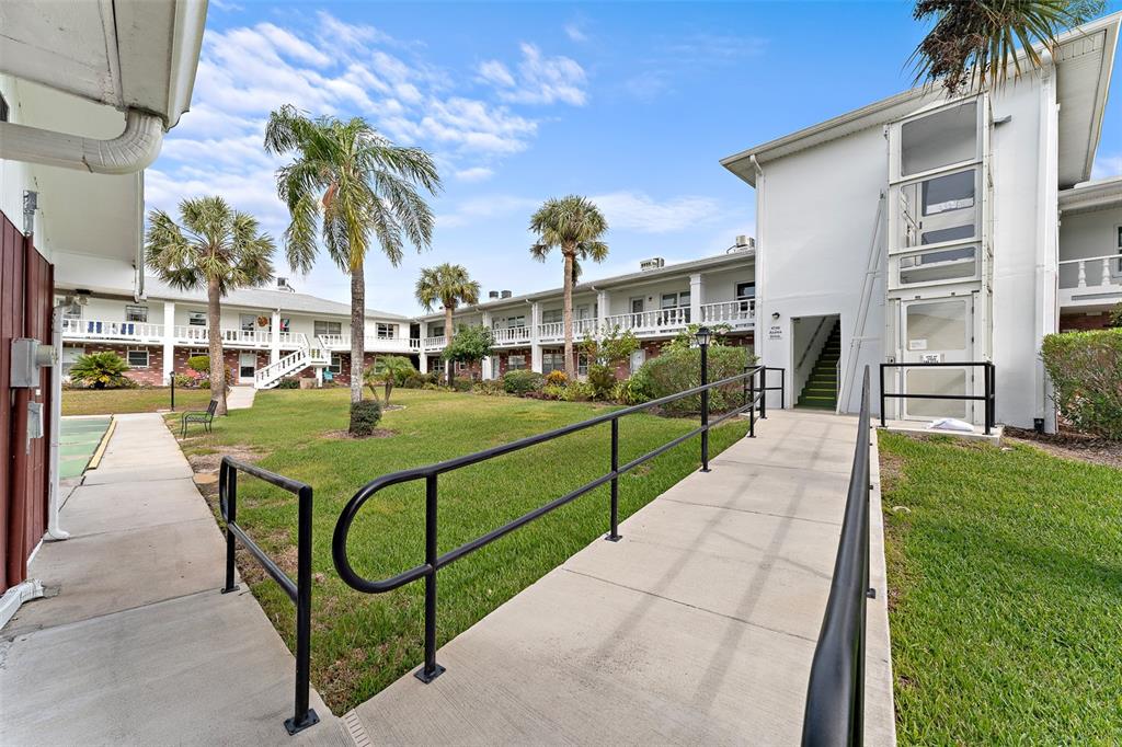 4746 Azalea Drive, Unit 105C New Port Richey, FL 34652 - Photo 22 of 27 a view of a swimming pool with a garden and plants