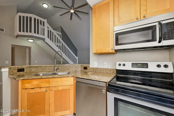 an empty room with wooden floor fireplace and windows