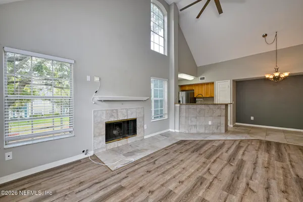 a view of an empty room with wooden floor fireplace and a window