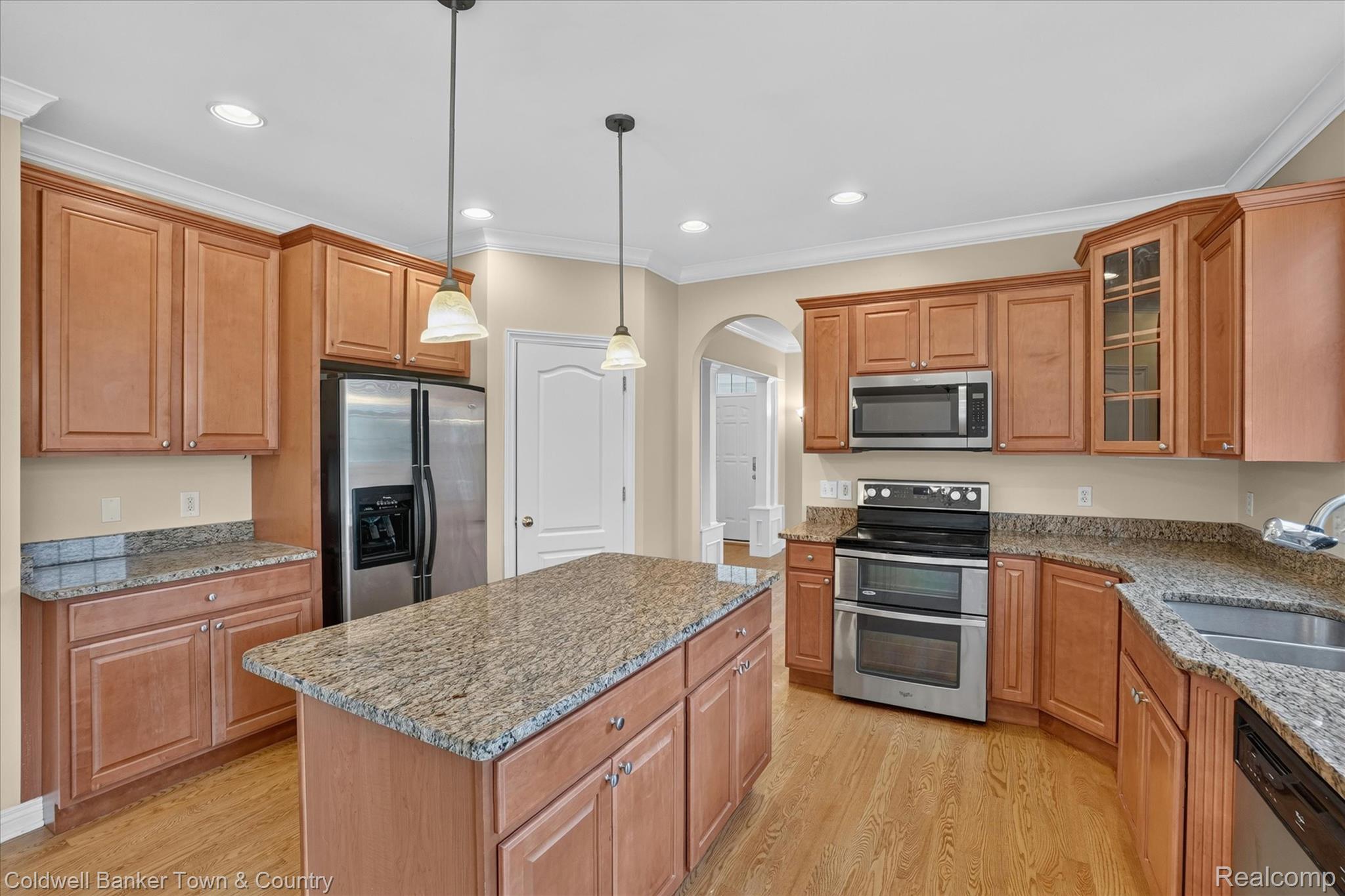 1725 Town Commons Drive Howell, MI 48855 - Photo 17 of 53 Kitchen featuring a central island with a granite countertop, wood-finish flooring, stainless steel appliances, pendant lighting, and abundant cabinetry
