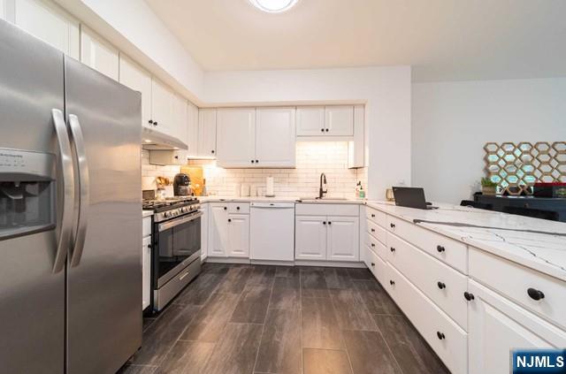 a kitchen with granite countertop white cabinets and stainless steel appliances