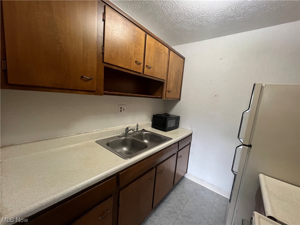 5651 Broadview Road, Unit C 07 Cleveland, OH 44134 - Photo 8 of 15 Kitchen featuring light tile floors, white fridge, sink, and a textured ceiling