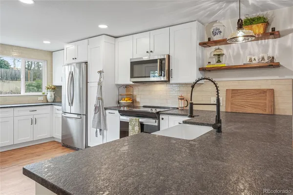 a kitchen with stainless steel appliances granite countertop a refrigerator a stove a sink and a microwave