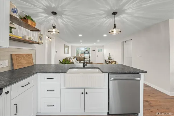 a kitchen with granite countertop a sink stainless steel appliances and white cabinets