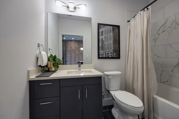 a bedroom with a bed a mirror on dresser and a chandelier