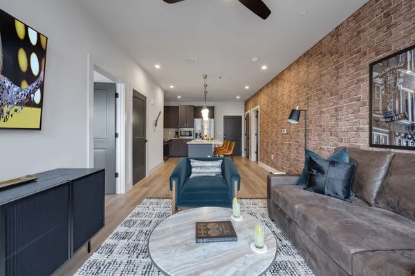 a living room with stainless steel appliances furniture a rug and a view of kitchen