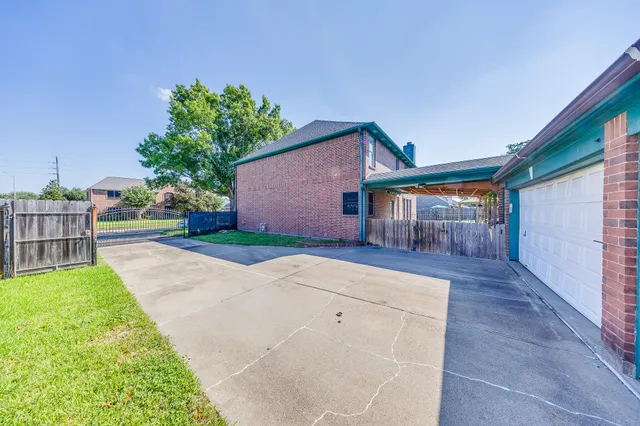 a backyard of a house with table and chairs plants and large tree