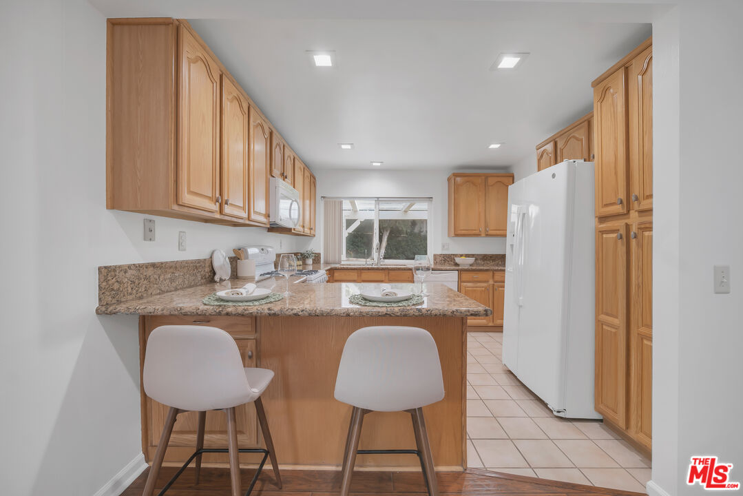 11700 Doral Avenue Porter Ranch, CA 91326 - Photo 22 of 65 a kitchen with stainless steel appliances granite countertop a refrigerator a stove a sink a dining table and chairs with wooden floor