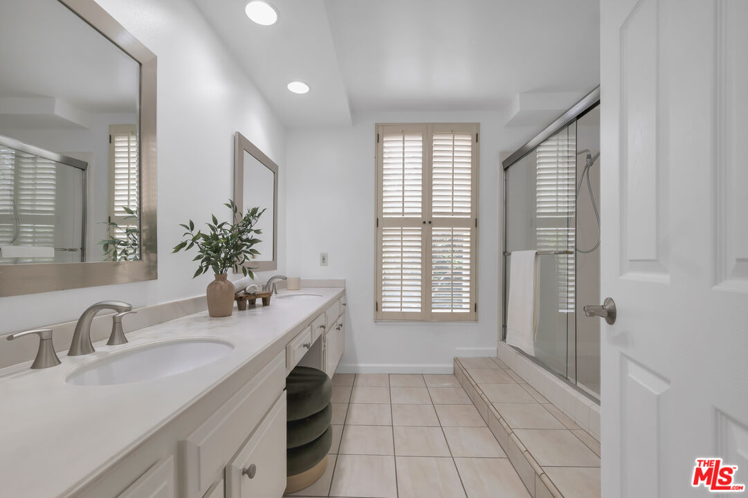 11700 Doral Avenue Porter Ranch, CA 91326 - Photo 34 of 65 a bathroom with a granite countertop sink a large mirror and a shower