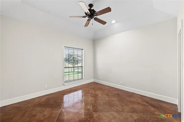 an empty room with windows and fan