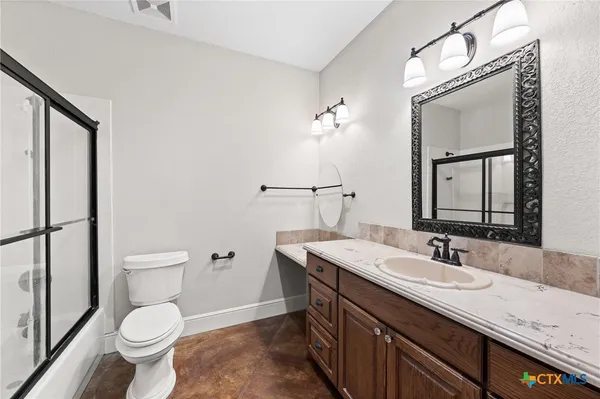 a bathroom with a granite countertop toilet sink and mirror