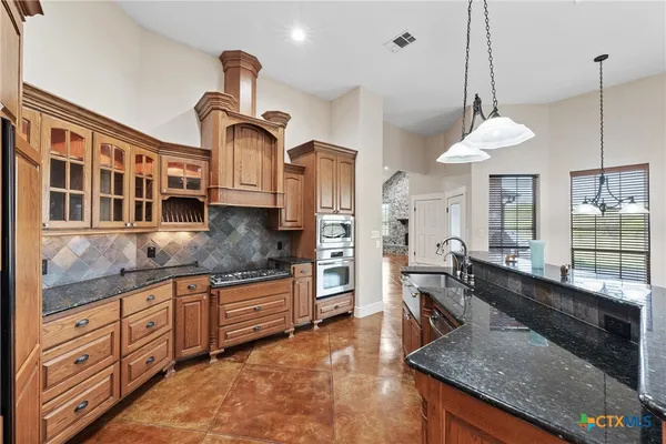 a kitchen with stainless steel appliances granite countertop a stove and a granite counter tops with white cabinets