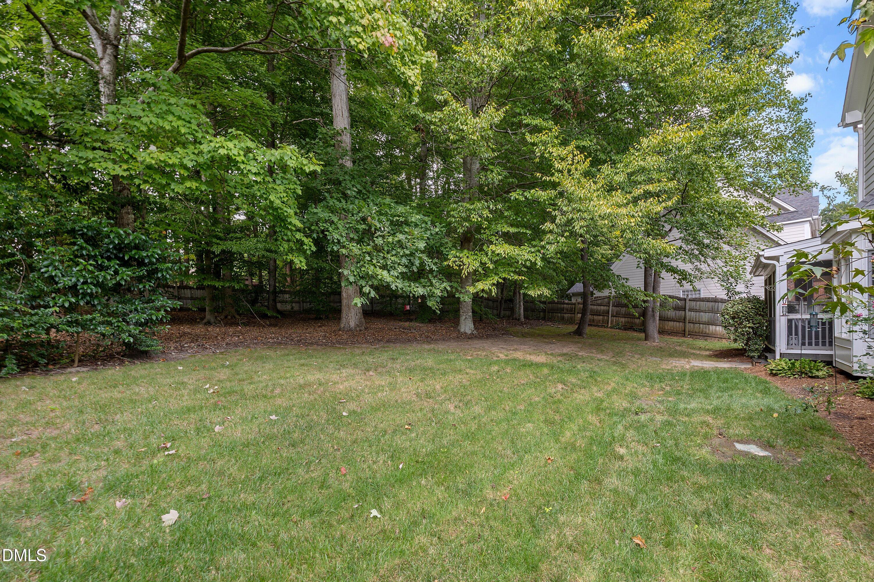 3914 Sterling Ridge Lane Durham, NC 27707 - Photo 57 of 66 Expansive backyard with a manicured lawn, mature trees, and a screened porch