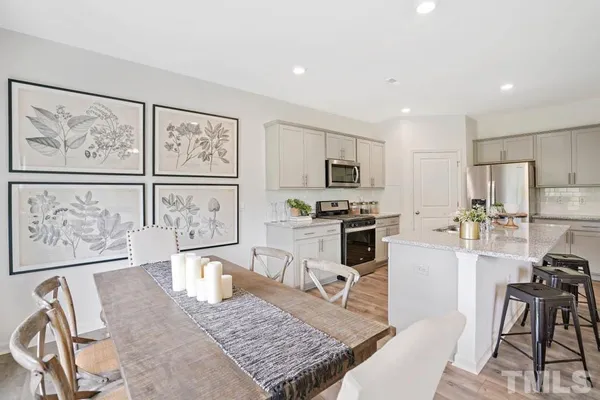 a kitchen with stainless steel appliances granite countertop a stove top oven a sink a dining table and chairs with wooden floor