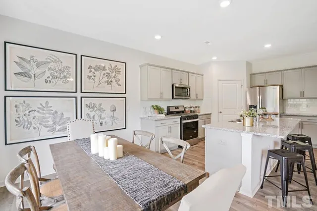 a kitchen with stainless steel appliances granite countertop a stove top oven a sink a dining table and chairs with wooden floor