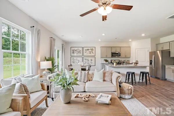 a living room with furniture kitchen view and a large window