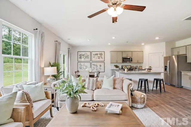 a living room with furniture kitchen view and a large window