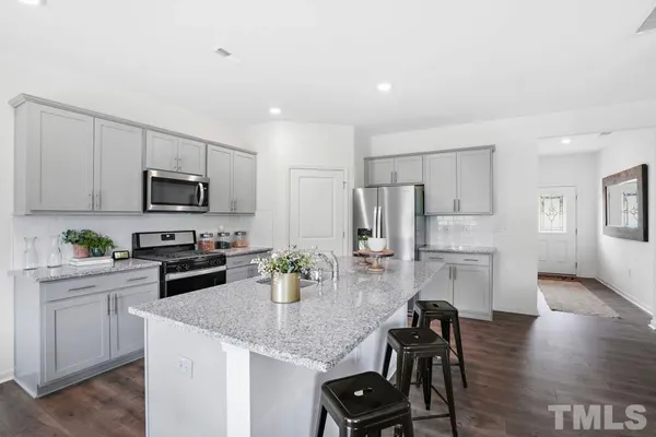 a kitchen with a refrigerator a stove a sink a dining table and chairs with wooden floor