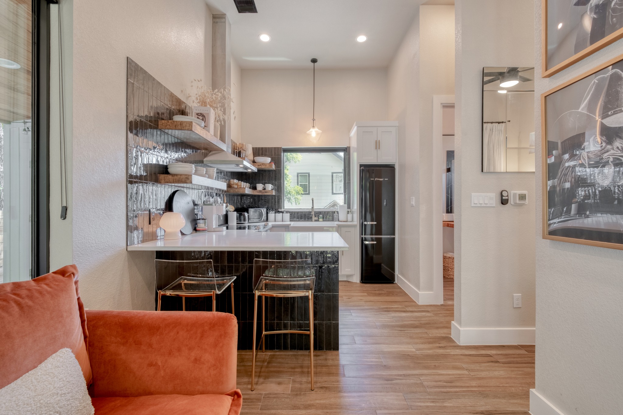 1904 East 16th Street, Unit 2 Austin, TX 78702 - Photo 7 of 20 Modern kitchen featuring a white countertop with an integrated breakfast bar, dark tile backsplash, open wood shelving, recessed lighting, and wood-finish flooring