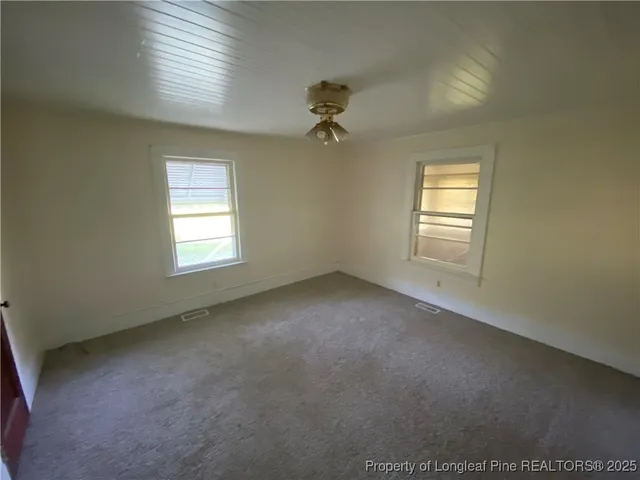 an empty room with windows and ceiling fan view