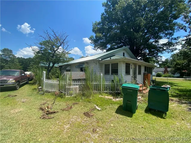 a backyard of a house with table and chairs a barbeque with potted plants and large trees
