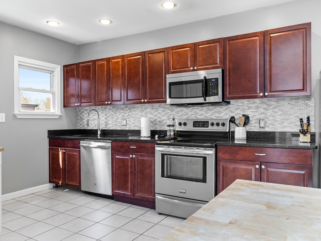 91-93 Rossmore Road, Unit 3 Boston, MA 02130 - Photo 8 of 25 a kitchen with stainless steel appliances granite countertop wooden cabinets a stove a sink and a microwave