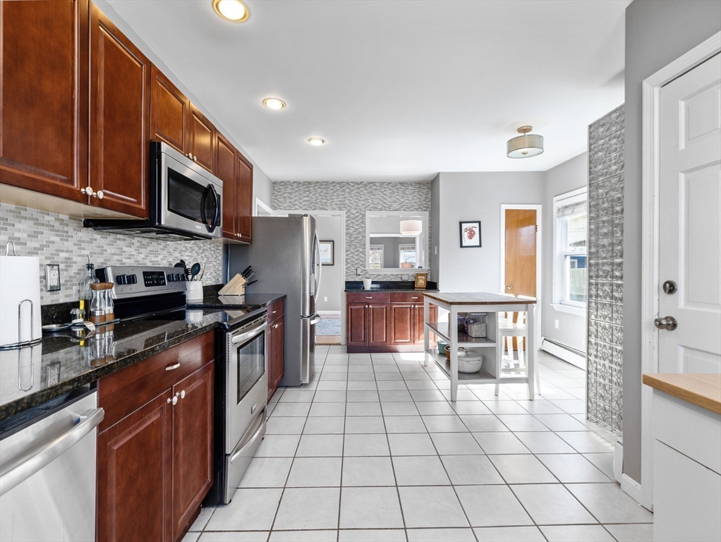 91-93 Rossmore Road, Unit 3 Boston, MA 02130 - Photo 9 of 25 a large kitchen with stainless steel appliances granite countertop a stove top oven a sink a dining table and chairs