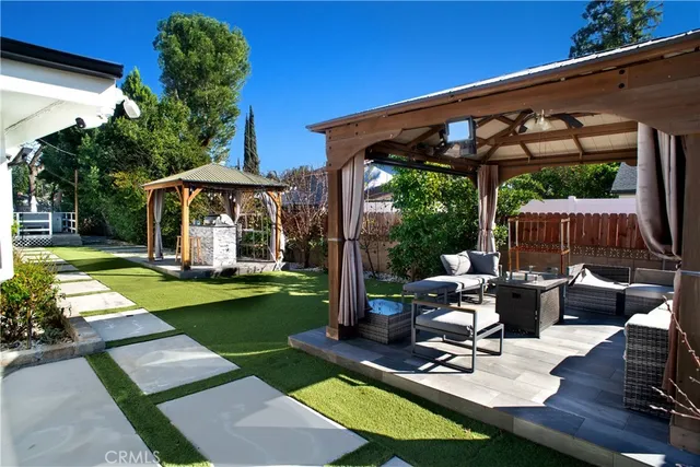 a view of a patio with couches table and chairs under an umbrella with a small yard
