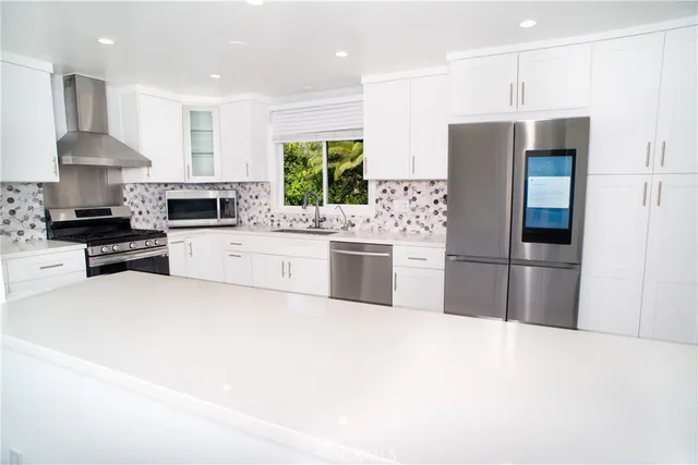a kitchen with stainless steel appliances a refrigerator a stove a sink and a refrigerator