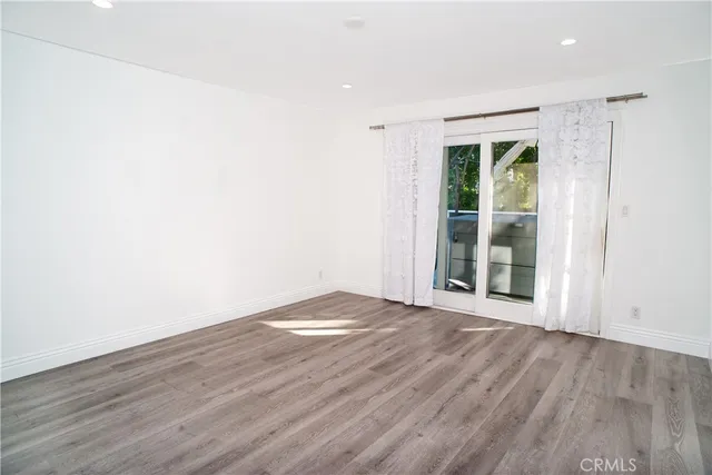 a view of an empty room with wooden floor and windows