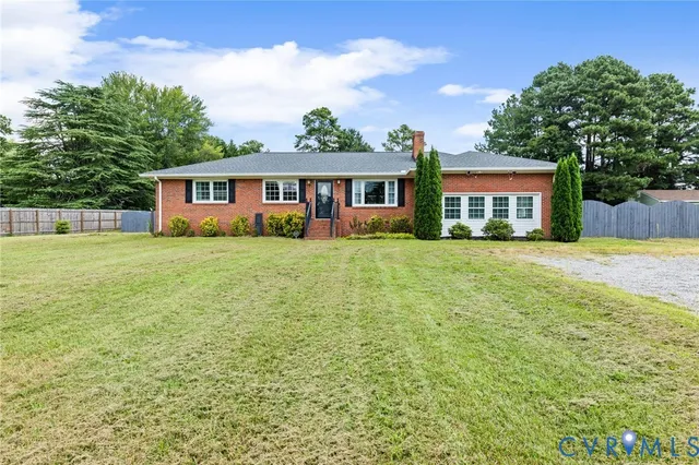 a view of a house with a yard and large trees