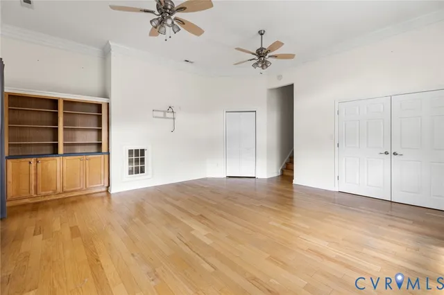 a view of an empty room with a window and wooden floor