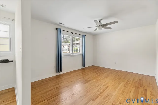 an empty room with windows and fan