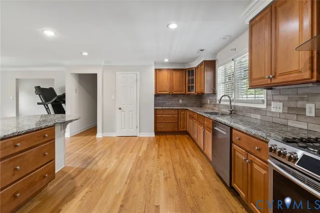 a large kitchen with stainless steel appliances granite countertop a lot of counter space and wooden floor