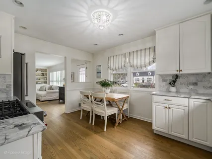 a kitchen with a dining table chairs and white cabinets