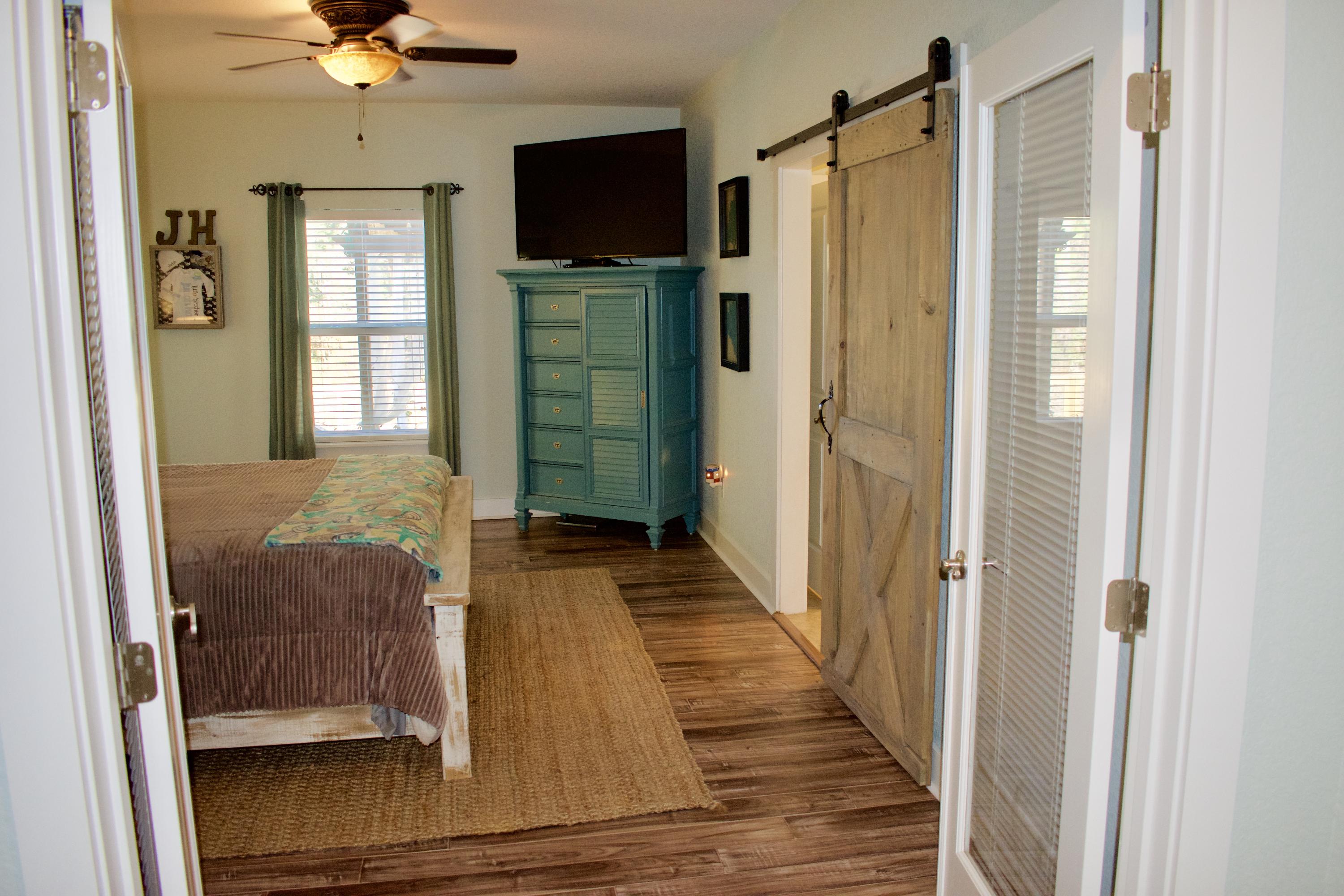 153 Spotted Dolphin Road Santa Rosa Beach, FL 32459 - Photo 20 of 36 a view of a hallway with wooden floor and cabinet with a flat screen tv