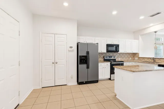 a kitchen with a refrigerator a stove top oven and white cabinets