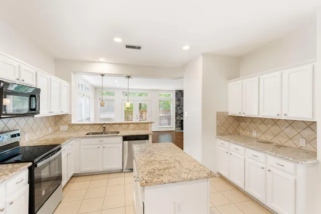 a kitchen with granite countertop a sink stove top oven and cabinets