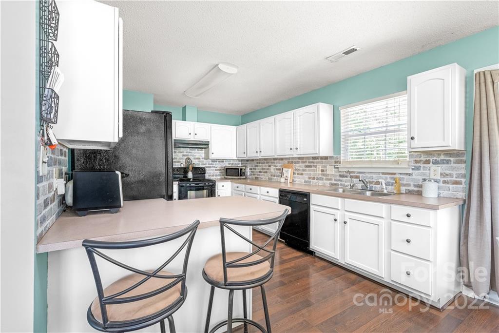 409 Funderburk Road Wingate, NC 28174 - Photo 8 of 22 a kitchen with stainless steel appliances kitchen island granite countertop a stove a sink dishwasher a microwave oven and white cabinets with wooden floor