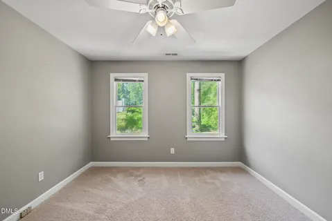 a view of an empty room with window and chandelier fan