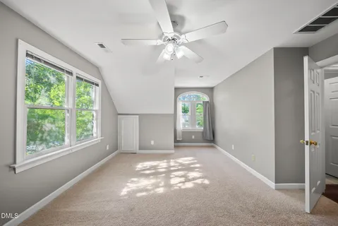 an empty room with windows and ceiling fan