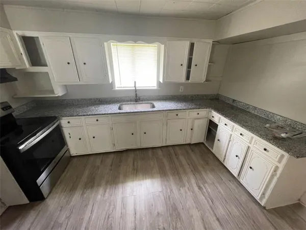 a kitchen with wooden floors and white cabinets