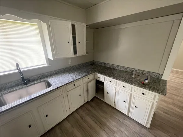 a kitchen with granite countertop white cabinets and a sink