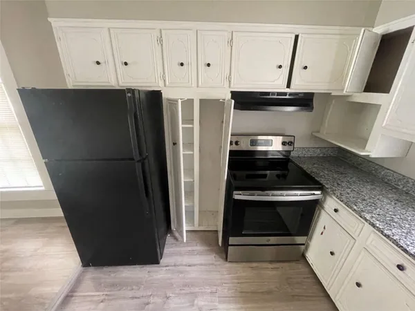 a kitchen with granite countertop white cabinets and stainless steel appliances