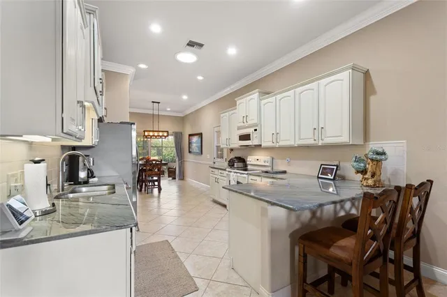 a kitchen with stainless steel appliances granite countertop a sink a stove a dining table and chairs