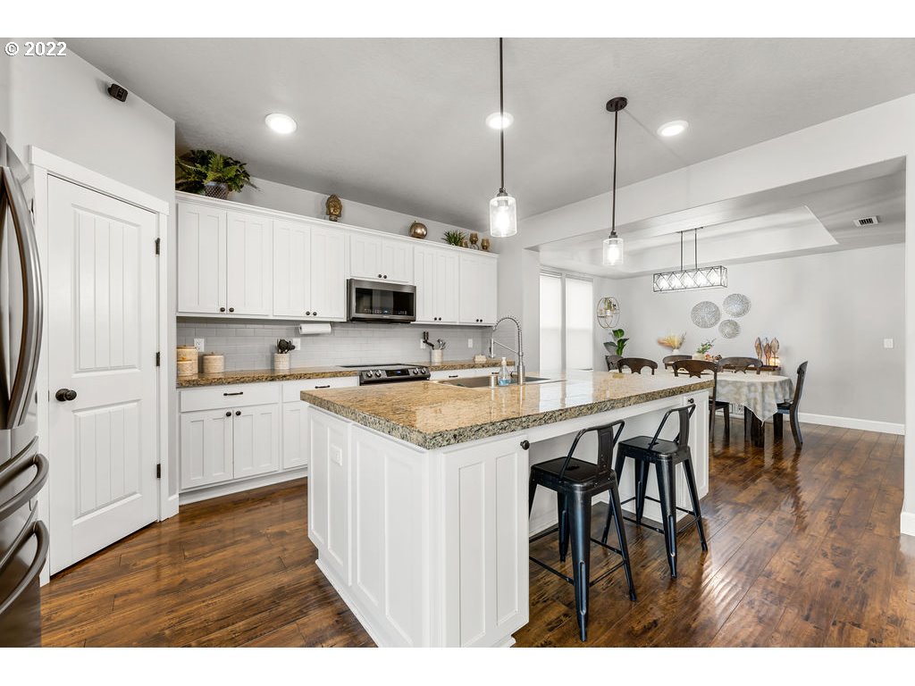 4593 North Noble Loop Ridgefield, WA 98642 - Photo 5 of 22 a kitchen with kitchen island granite countertop wooden floors and white appliances