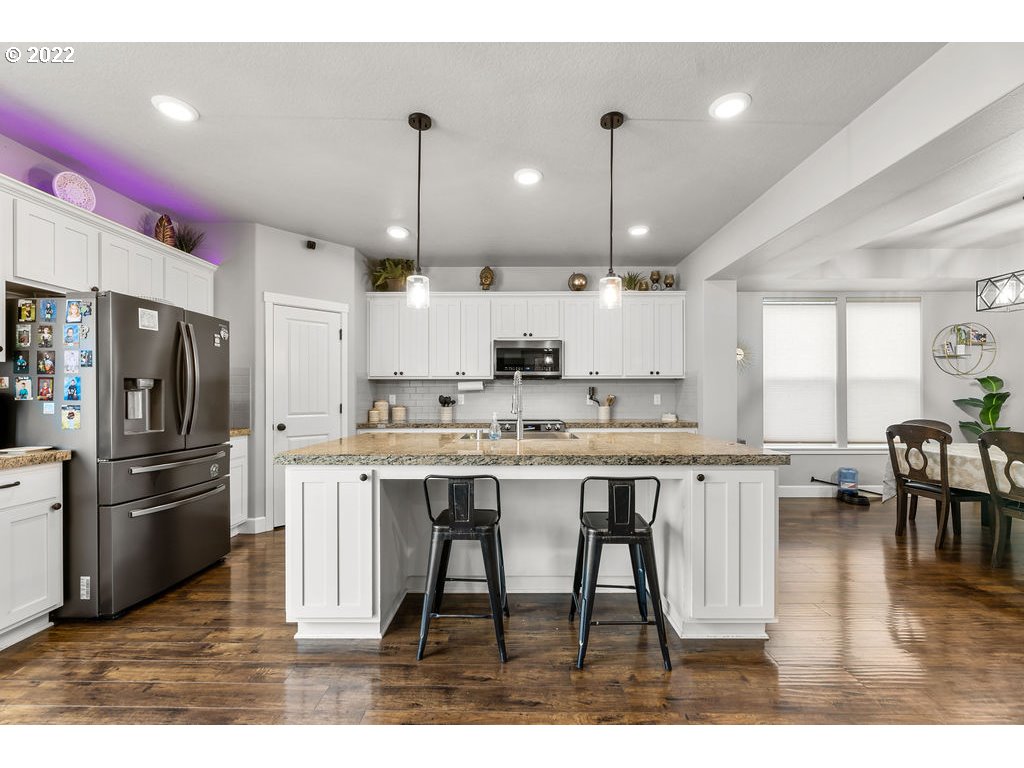 4593 North Noble Loop Ridgefield, WA 98642 - Photo 6 of 22 a kitchen with stainless steel appliances kitchen island granite countertop a table chairs sink and cabinets