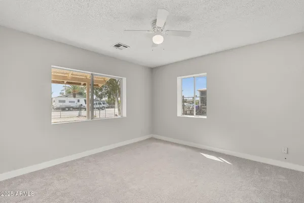 an empty room with windows and ceiling fan