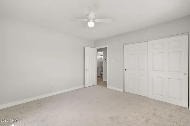 an empty room with a ceiling fan and a window