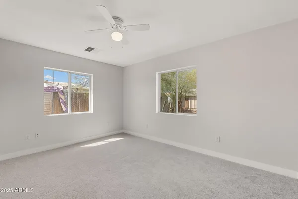 an empty room with windows and ceiling fan